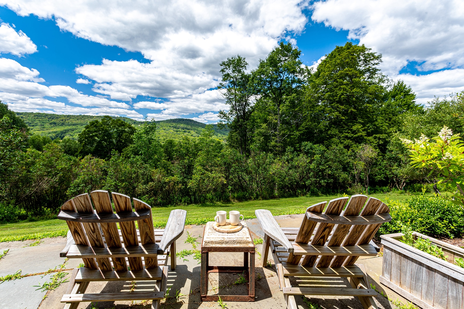 Wooden,Outdoor,Chairs,On,Patio,Overlooking,Green,Mountains,Under,Blue