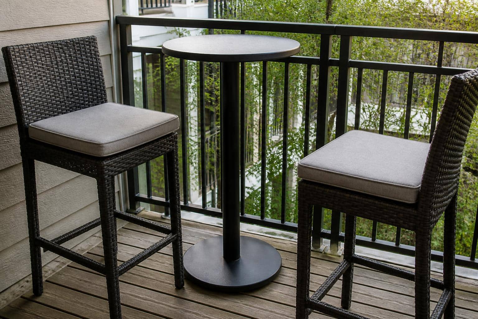 Round pedestal base with weighted disc supporting a small bistro table on tiled balcony flooring