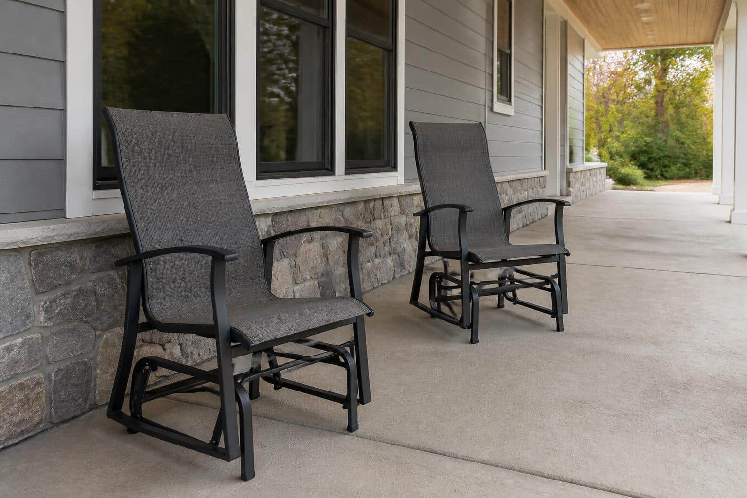 Wide view of a Charlotte back patio with two outdoor glider chairs correctly spaced along a wall with clear walking paths and a side table between them