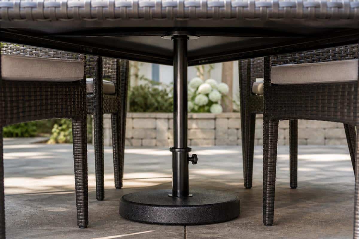 Weighted umbrella base aligned beneath a Charlotte patio dining table
