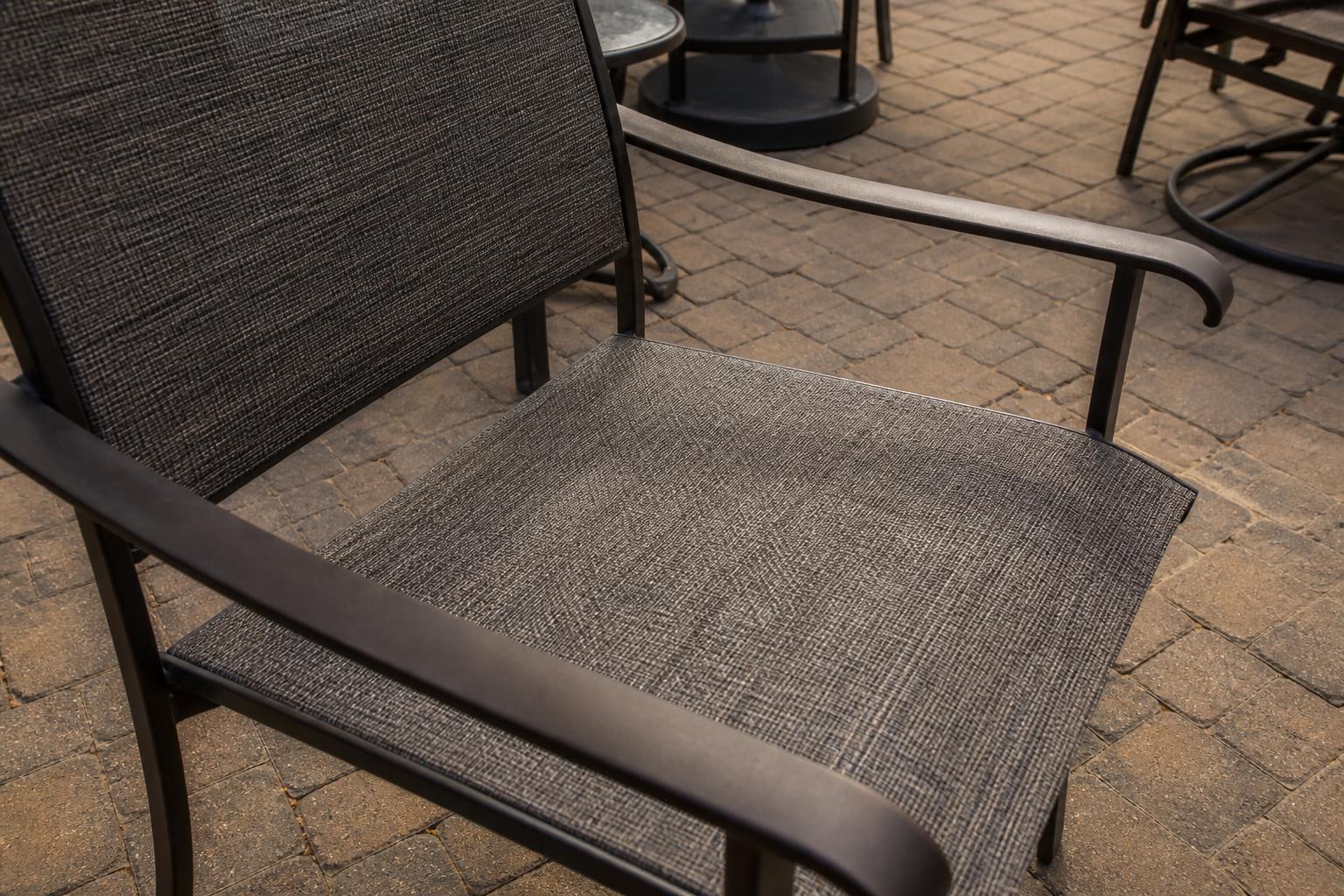 Close view of a sling patio chair showing the fabric panel stretched between aluminum side rails