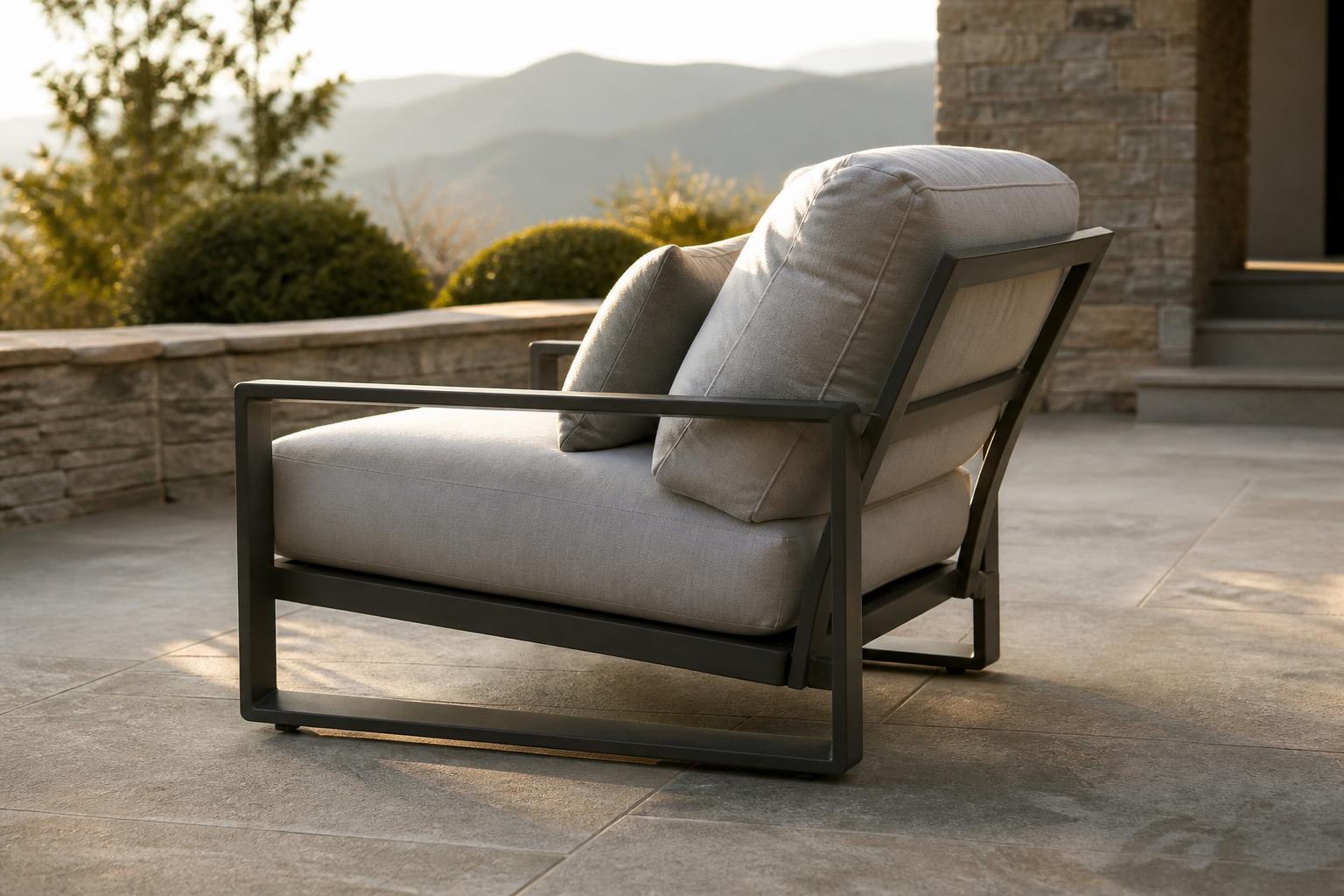 Aluminum-framed outdoor lounge chair with a thick light gray seat cushion and back cushion on a stone patio